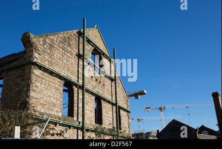 Old listed building in the Limekiln docks area of Bristol supported by an external metal structure against a blue sky. Stock Photo