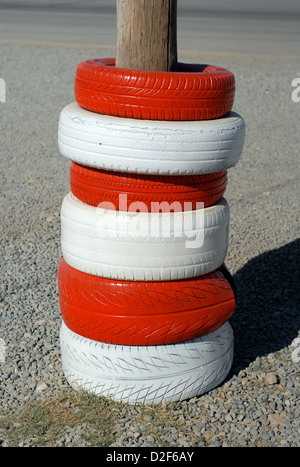 red and white painted car tyres protecting a telephone pole at a petrol station in morocco Stock Photo