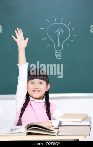 Schoolgirl raising hand in classroom Stock Photo - Alamy