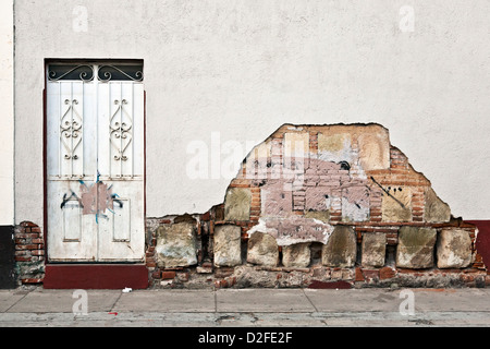 elegant old entrance door in deteriorated white plaster wall revealing old stone & brick construction underneath Oaxaca Mexico Stock Photo