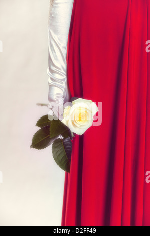 a woman in a red dress is holding a white rose in her hand