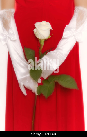 a woman in a red dress is holding a white rose in her hands Stock Photo