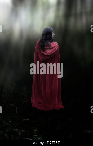 a woman with a red cloak in the woods Stock Photo