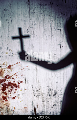 shadow of a person with a crucifix on a bloody white wall Stock Photo