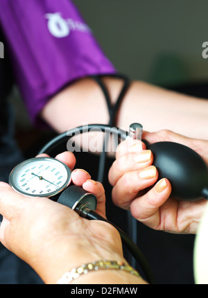 Female blood pressure being taken in UK GP Health Centre by female doctor Stock Photo