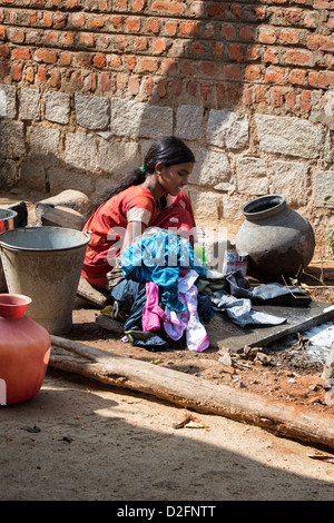 Indian teenage girl washing clothes by hand outside her village home. Andhra Pradesh, India Stock Photo
