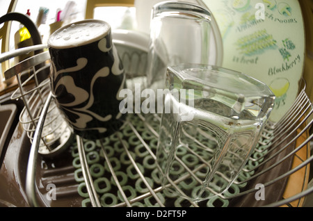 clean mug and glasses on draining board inside kitchen chores of the day emphasized distorted Stock Photo