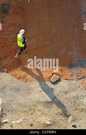 Construction workers - Building construction worker walking across an inner city urban building site, Europe Stock Photo