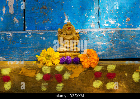 Lord Shiva statue and flower petals outside village temple doorway. India Stock Photo