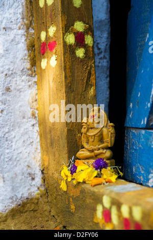 Lord Shiva statue and flower petals outside village temple doorway. India Stock Photo