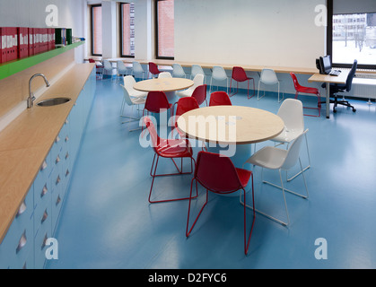 Modern meeting room with colorful chairs, round table, windows and row of office folders on shelf. Tartu Health Care College in Stock Photo