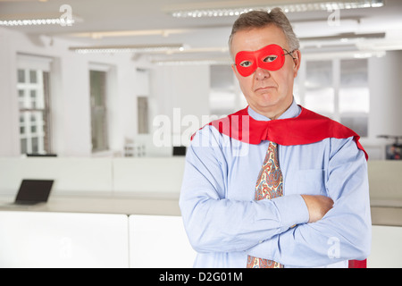 Portrait of serious businessman in superhero costume in office Stock Photo