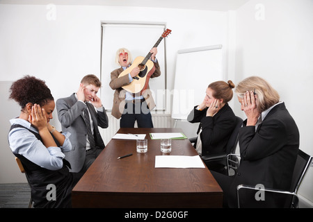 Businessman playing guitar in business meeting Stock Photo