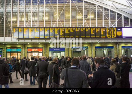 Commuters people looking at departure boards full of train delays cancellations at Kings Cross station, London, UK in the rush hour Stock Photo