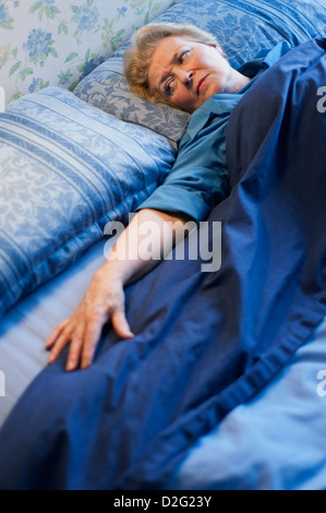 Mature woman lying in bed and looking at the empty space next to her Stock Photo