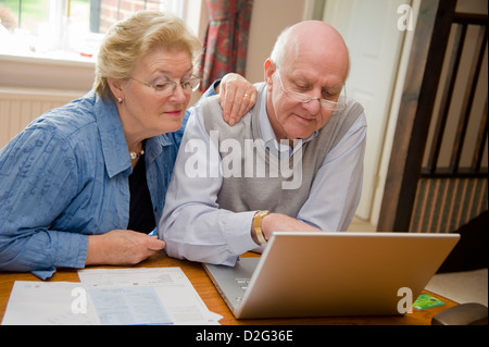 Happy seniors using the internet on a laptop online Stock Photo