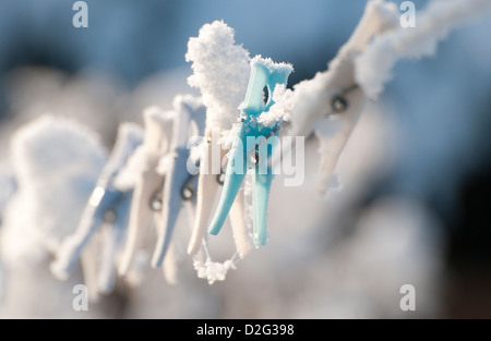 snow covered clothes pegs on linen line Stock Photo