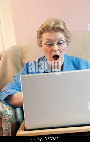 Senior woman using her laptop with a shocked expression Stock Photo