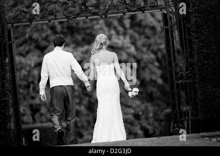 Black and white landscape photo of a Bride and Groom walking away from the camera outside