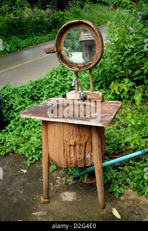 A working sink made from an old hollowed out tree trunk with a mirror along side the road in koh chang thailand Stock Photo