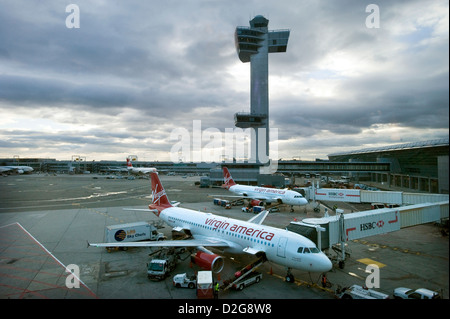 Two Virgin America Airbus A320 jet Aircraft stand in front of the Control Tower at John F. Kennedy Airport, JFK Airport, New York, USA at dusk as they are loaded for their next flights. Stock Photo