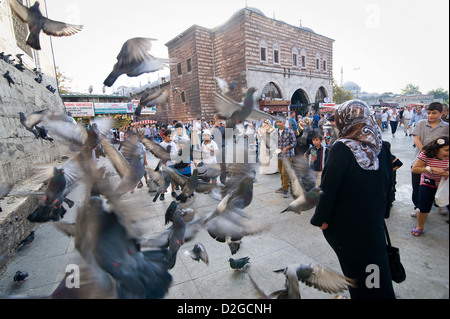 Turks and tourists alike like to feed the millions of pigeons in Eminonu. In the background you see the Egyptian Spice Bazaar. Stock Photo