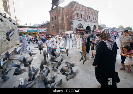 Turks and tourists alike like to feed the millions of pigeons in Eminonu. In the background you see the Egyptian Spice Bazaar. Stock Photo