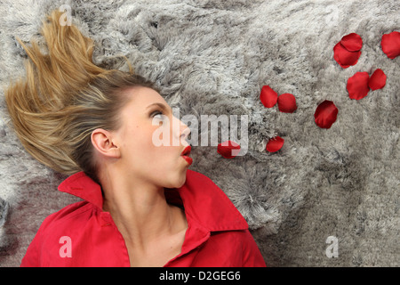 Laid woman blowing on rose petals Stock Photo