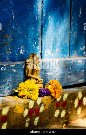 Lord Shiva statue and flower petals outside village temple doorway. India Stock Photo