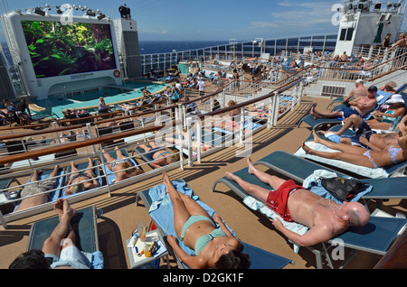 Passengers sunbathing at sea on the aft deck of the cruise ship Norwegian Epic. Stock Photo