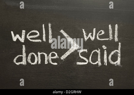 interpretation of famous quote of B. Franklin 'Well done is better than well said' handwritten on blackboard Stock Photo