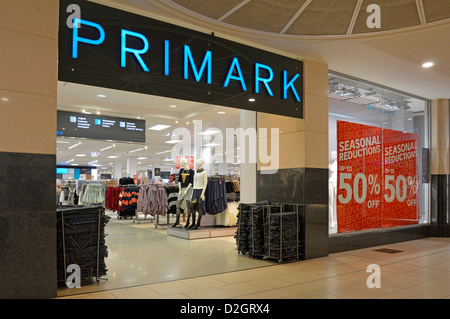 Clothing store Primark sign above entrance in indoor shopping mall with up to 50% seasonal reductions posters in windows Stock Photo