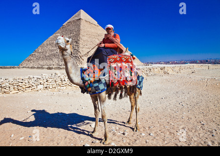 Camel driver poses in front of Pyramid of Khafre or Chefren, second-largest ancient Egyptian Pyramid of Giza near Cairo, Egypt. Stock Photo