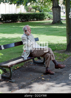 Elderly man using mobile phone  in Dane John Park, Canterbury England Stock Photo