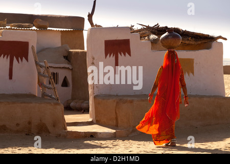 India, Rajasthan, Thar Desert, Indian woman carrying traditional water pot back to village home Stock Photo