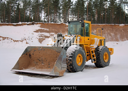 Yellow wheel loader at sand pit in winter snow. Stock Photo