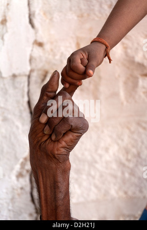 India, Rajasthan, Jodhpur, very old man's hand being held young girl's hand Stock Photo