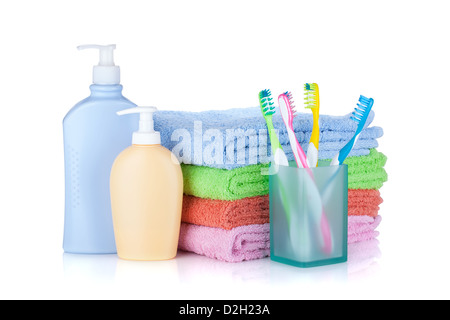 Four colorful toothbrushes, cosmetics bottles and towels. Isolated on white background Stock Photo