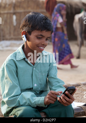 India, Uttar Pradesh, Agra, Child in school uniform using smartphone, wearing bluetooth headset Stock Photo