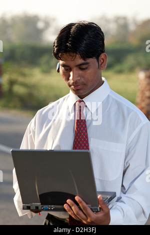 India, uttar Pradesh, Agra Indian businessman using laptop and wearing bluetooth headset Stock Photo