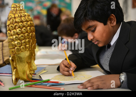 An eleven year old boy drawing a mask in an art lesson at Pates Grammar School in Cheltenham, Gloucestershire UK