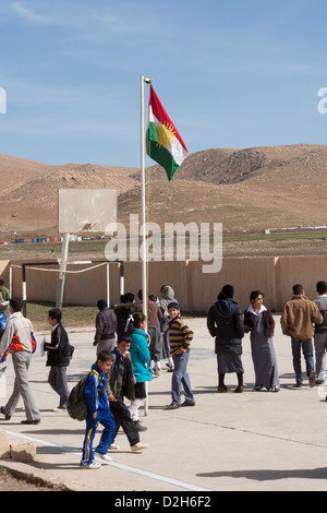 Primary and senior students in playground outside Iraqi Kurdish school in Northern Iraq  with Kurdistan flag Stock Photo