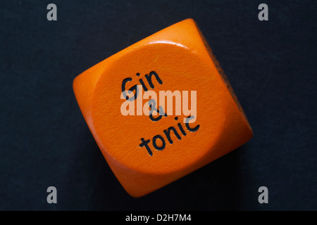 throw of an orange coloured drinking dice showing gin & tonic isolated on black background Stock Photo