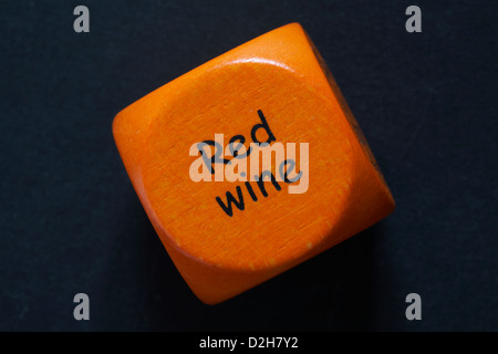 throw of an orange coloured drinking dice showing red wine isolated on black background Stock Photo
