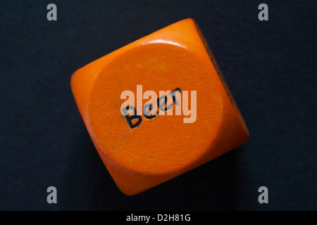 throw of an orange coloured drinking dice showing beer isolated on black background Stock Photo