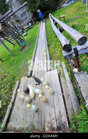 A woman playing ninepins on an open-air rustic bowling alley in the alps near the town of Kandersteg Stock Photo