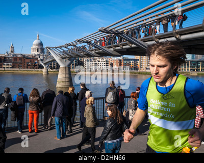 a young man running under millenium bridge in a sunny day
