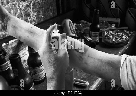 Heroin drug user injects his arm using a hypodermic syringe in a dirty bedroom (B&W - see D2HT21 for colour alternative)