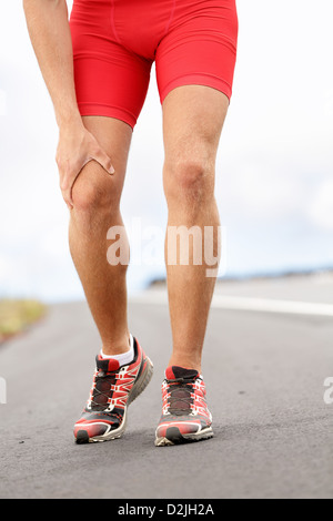 Low section of male runner having knee problems during exercise Stock Photo