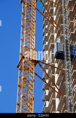 Modern apartment skyscraper under construction with cranes attached to it. Stock Photo